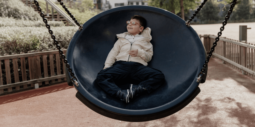 Jongen van ongeveer 8 jaar ligt in een grote schommel.