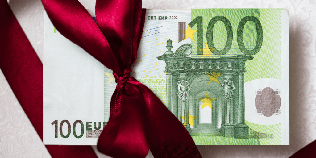 Een 100 eurobriefje met een donkerrood strikje rond.