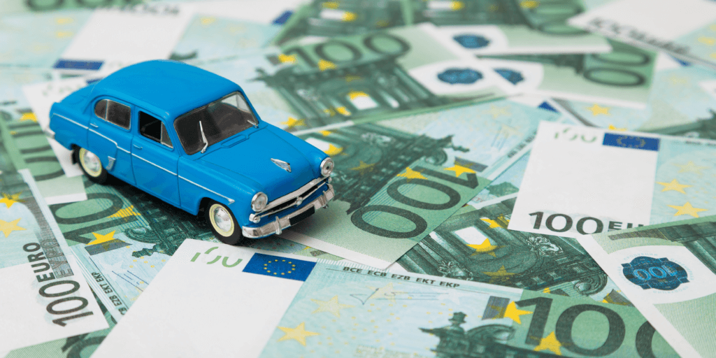 Verspreide briefjes van 100 euro met een blauw speelgoedautootje erop.