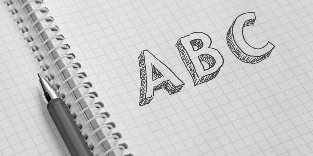 Notitieblok met ruitjes met de tekst "ABC" en een balpen.